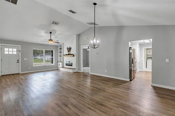 a view of a big room with wooden floor a chandelier and windows