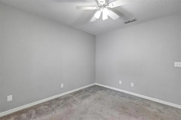 an empty room with a fan & a chandelier fan