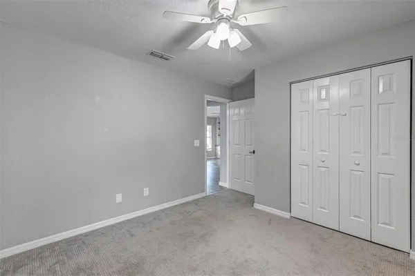 a view of an empty room and a chandelier fan