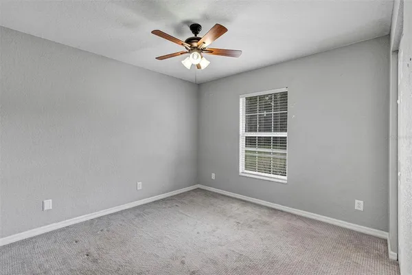 an empty room with window and ceiling fan