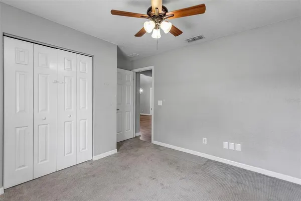 an empty room with closet and a chandelier fan