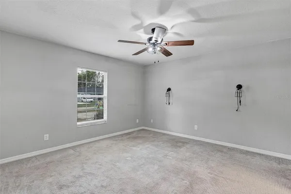 an empty room with windows and fan