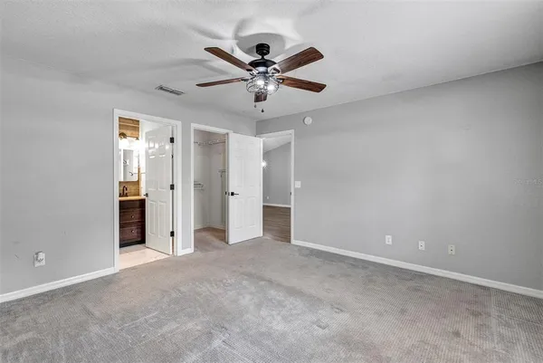 an empty room with closet and a ceiling fan