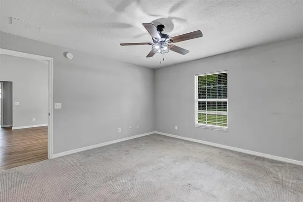 an empty room with windows and fan