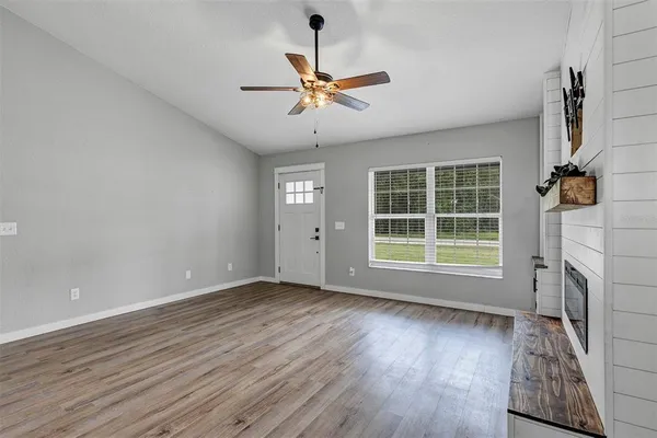 a view of empty room with wooden floor and fan