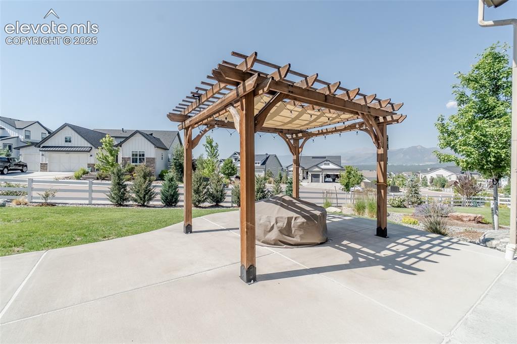 1061 Native Dancer Terrace Colorado Springs, CO 80921 - Photo 32 of 50 Expansive concrete patio featuring a wood pergola with a fabric canopy
