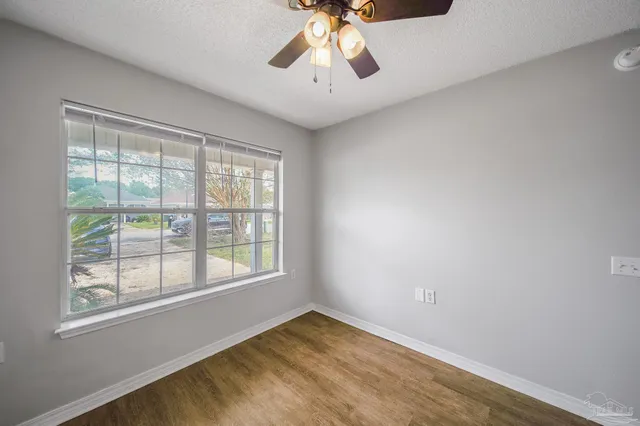 a view of an empty room with window and chandelier fan