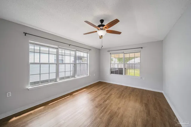 a view of empty room with wooden floor and fan