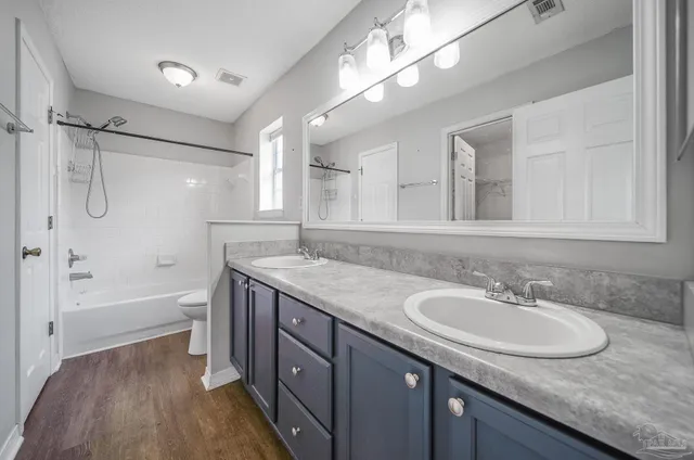a bathroom with a granite countertop sink a mirror a bathtub and shower