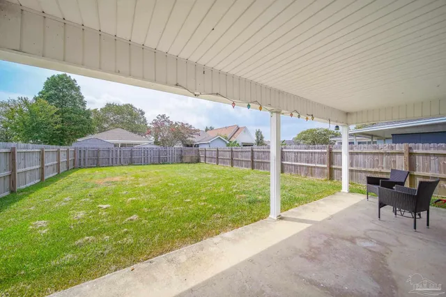 a view of a backyard with table and chairs potted plants and wooden fence