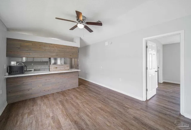 a view of kitchen and empty room with wooden floor