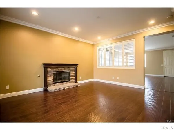 a view of an empty room with a fireplace and wooden floor
