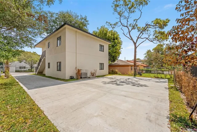 a view of a white house with a yard and large tree