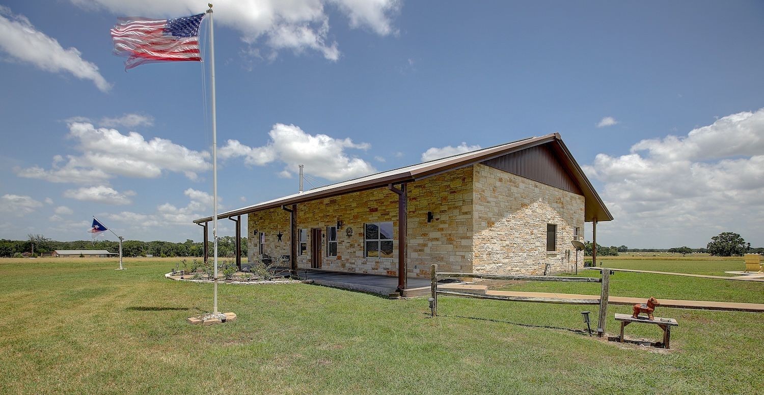 9414 Laird Road Round Top, TX 78954 - Photo 3 of 50 Side view of the home facade showing patriotic flags displayed with front/back porches with views