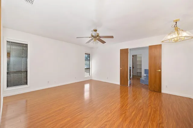 a view of an empty room with window and wooden floor