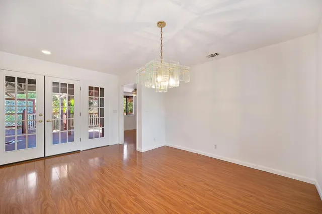 a view of an empty room with window and wooden floor