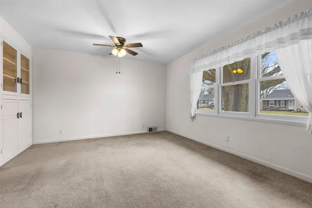 an empty room with windows and fan