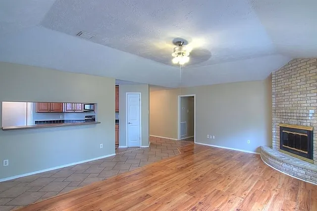 a view of a livingroom with a fireplace a ceiling fan and wooden floor