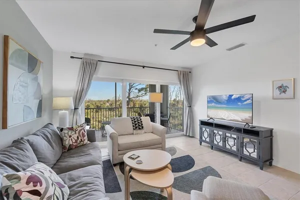 a living room with furniture a ceiling fan and a large window