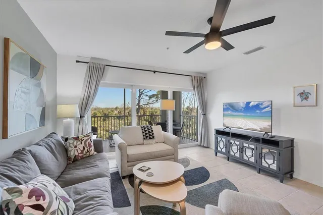 a living room with furniture a ceiling fan and a large window
