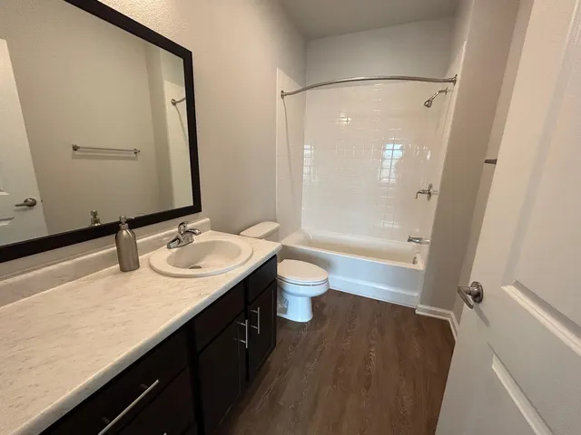 a bathroom with a granite countertop sink a toilet a mirror and shower