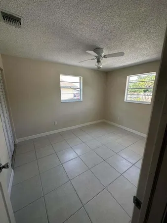 en empty room with windows and ceiling fan