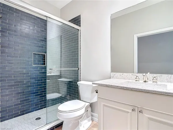 a bathroom with a granite countertop toilet sink and mirror