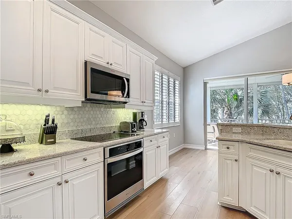 a kitchen with granite countertop white cabinets a window a sink and a oven