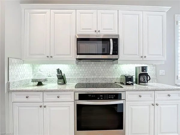 a kitchen with granite countertop white cabinets and a stove