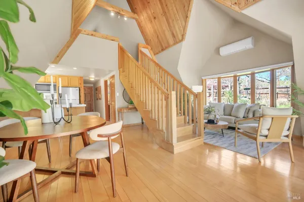 a dining room with furniture floor to ceiling windows and wooden floor