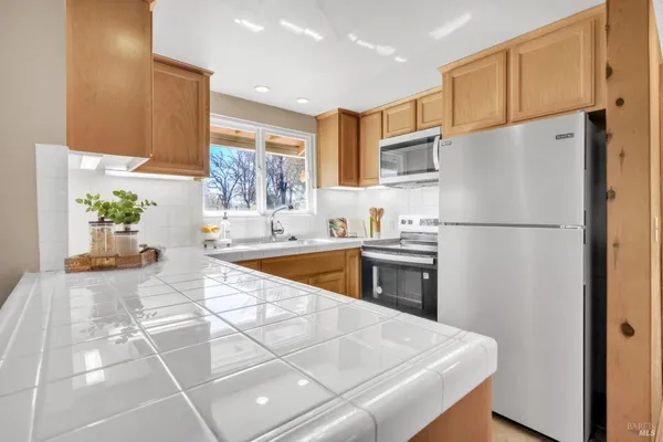 a kitchen with stainless steel appliances granite countertop a refrigerator a sink and a stove