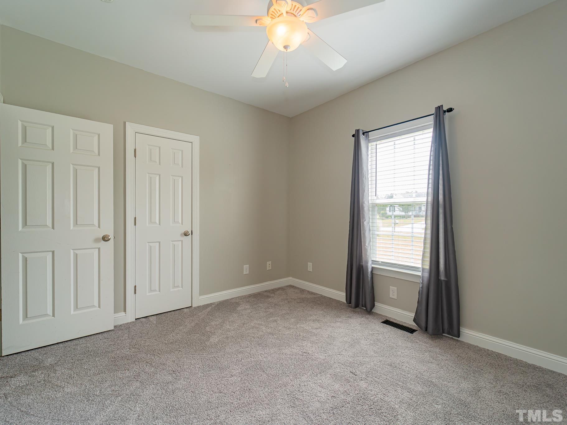 7730 La Finca Road Elm City, NC 27822 - Photo 23 of 29 an empty room with a chandelier fan and windows
