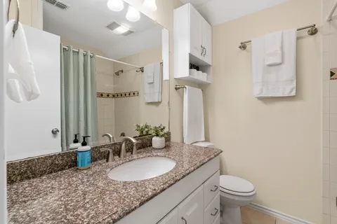 a bathroom with a granite countertop sink a mirror and a toilet