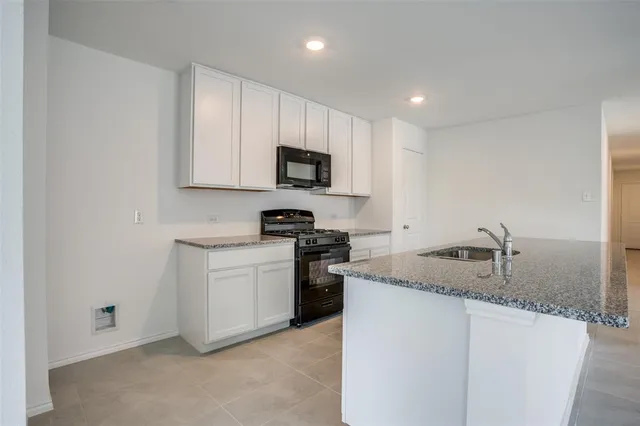 a kitchen with granite countertop white cabinets and stainless steel appliances