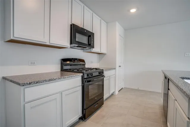a kitchen with stainless steel appliances granite countertop white cabinets sink and a granite counter top