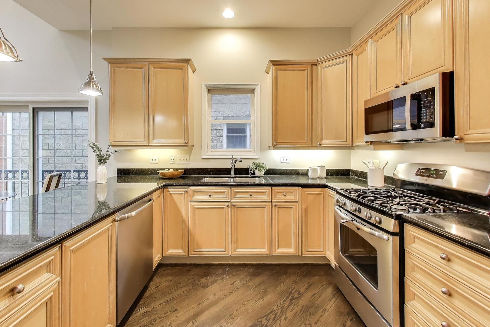 1312 West Fletcher Street, Unit 3W Chicago, IL 60657 - Photo 6 of 30 a kitchen with stainless steel appliances granite countertop a stove a sink and a microwave