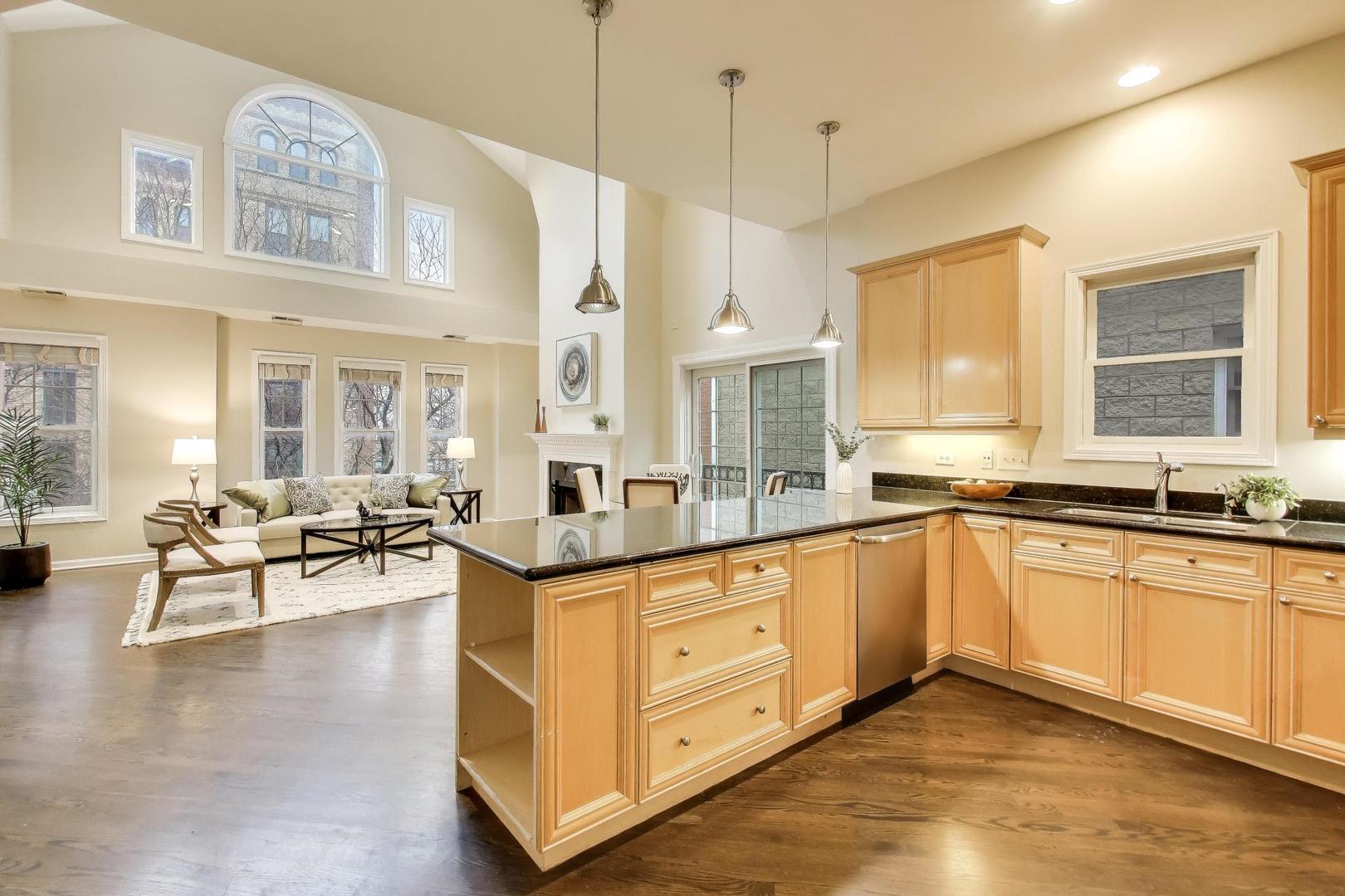 1312 West Fletcher Street, Unit 3W Chicago, IL 60657 - Photo 7 of 30 a large kitchen with cabinets a sink a window and chairs