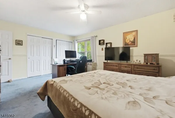 a large bedroom with a bed and a flat tv screen on dresser