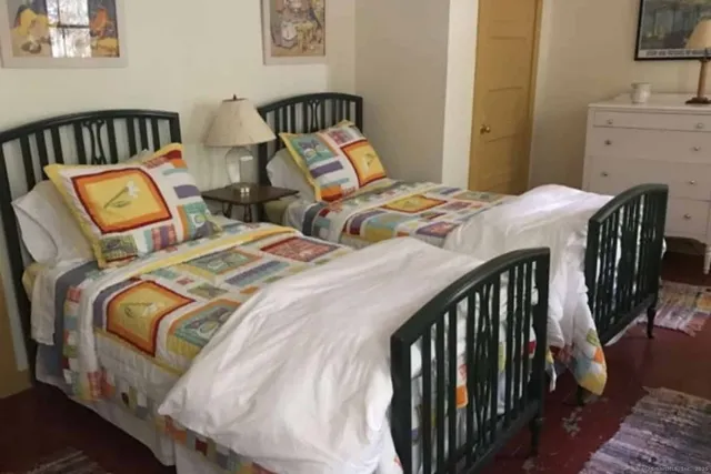 a bedroom with two beds and wooden floor