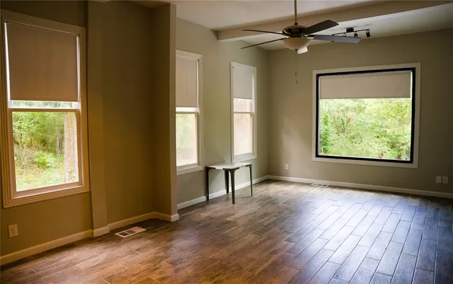 a view of an empty room with a window and wooden floor
