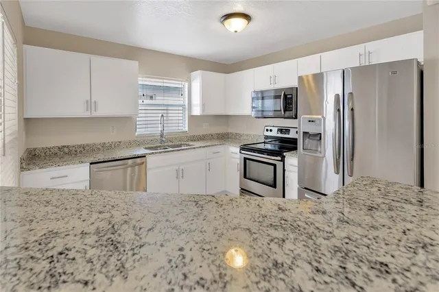 a kitchen with stainless steel appliances white cabinets white stove a microwave and a refrigerator