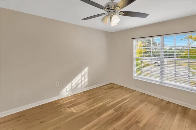 a view of an empty room with a window and wooden floor