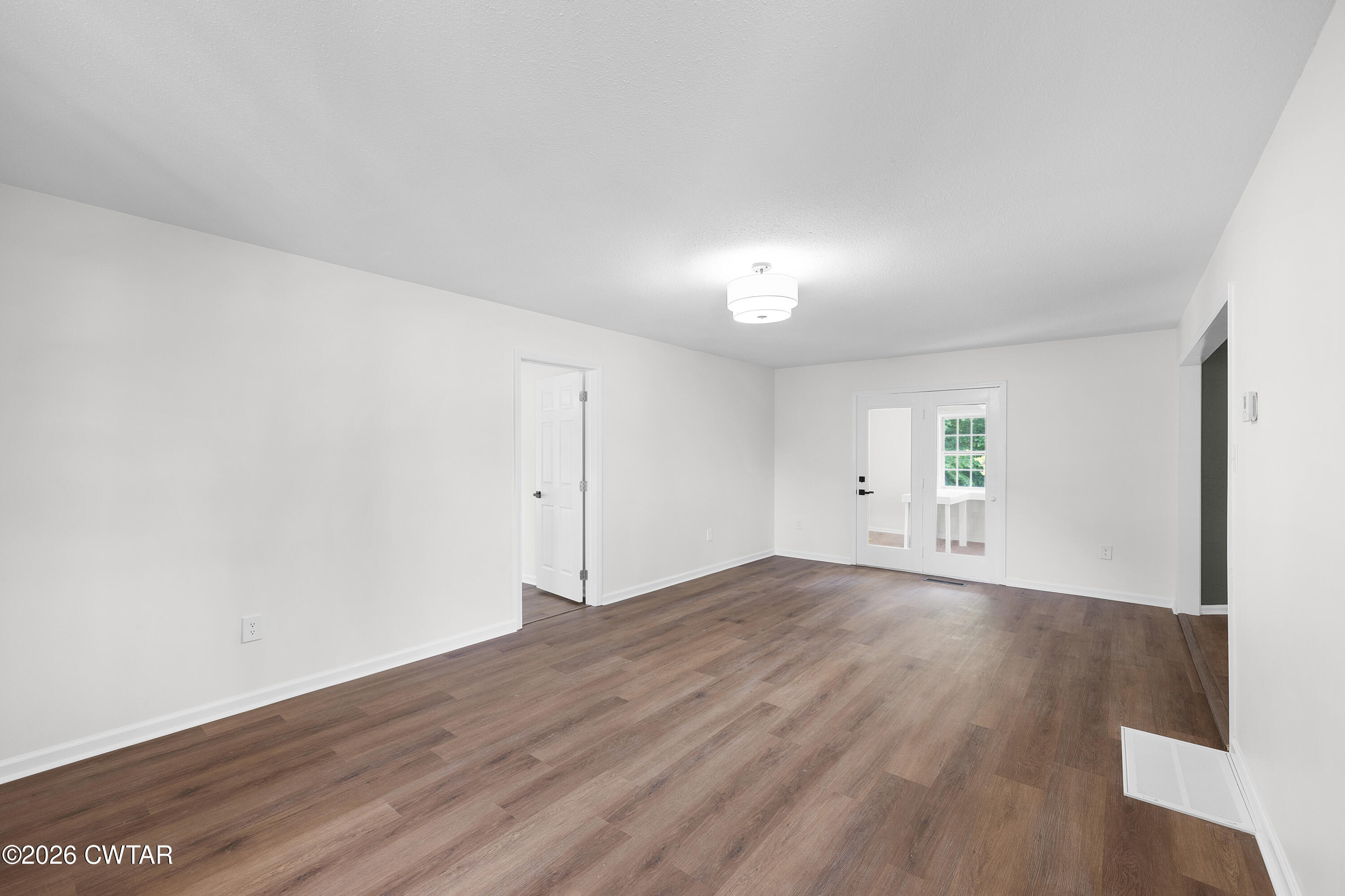 3075 Old Huntingdon Road Lexington, TN 38351 - Photo 2 of 19 an empty room with wooden floor and windows