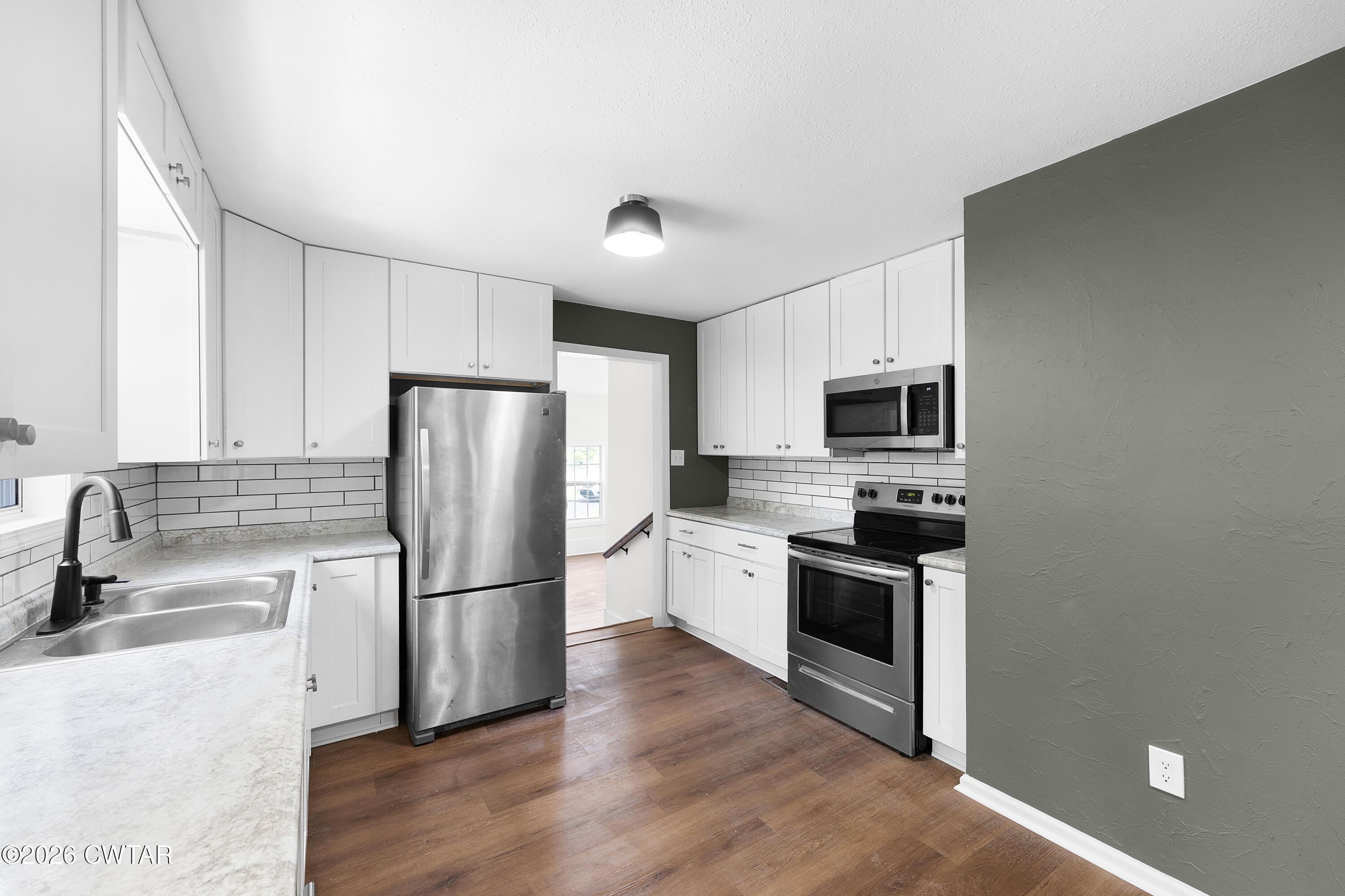 3075 Old Huntingdon Road Lexington, TN 38351 - Photo 5 of 19 a kitchen with stainless steel appliances granite countertop a refrigerator stove a sink and a oven with wooden floor