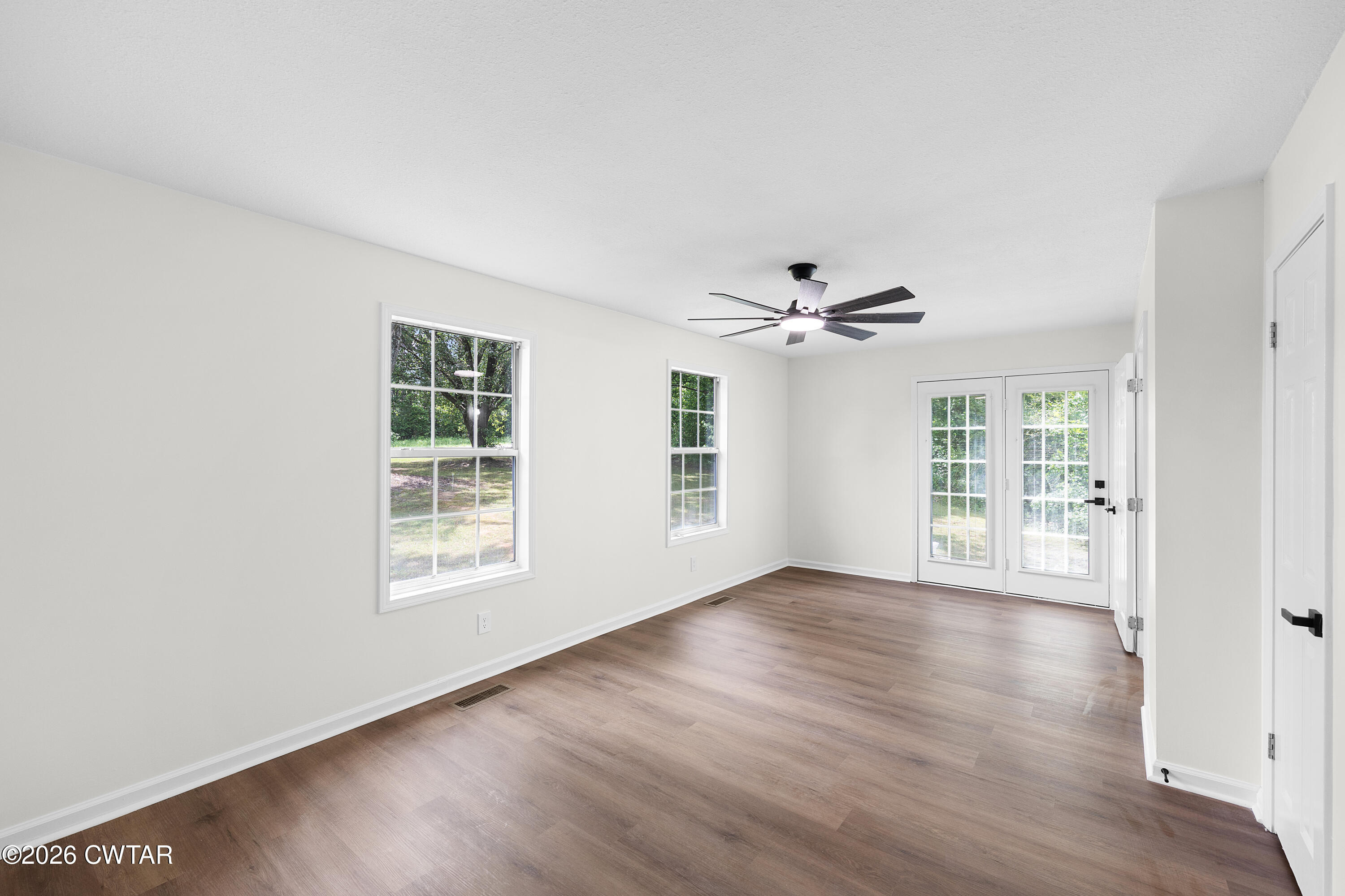 3075 Old Huntingdon Road Lexington, TN 38351 - Photo 8 of 19 an empty room with wooden floor fan and windows