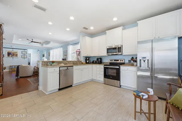 a kitchen with granite countertop a refrigerator oven a sink and white cabinets