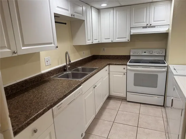 a kitchen with granite countertop a sink dishwasher a stove and cabinets