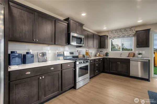a kitchen with stainless steel appliances granite countertop wooden cabinets a stove top oven a sink and dishwasher