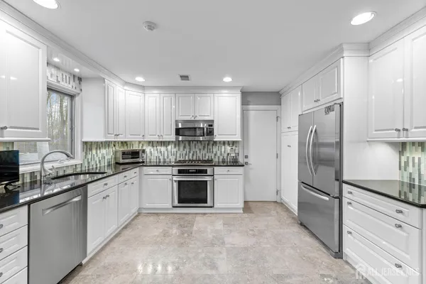 a kitchen with stainless steel appliances granite countertop a refrigerator sink and stove