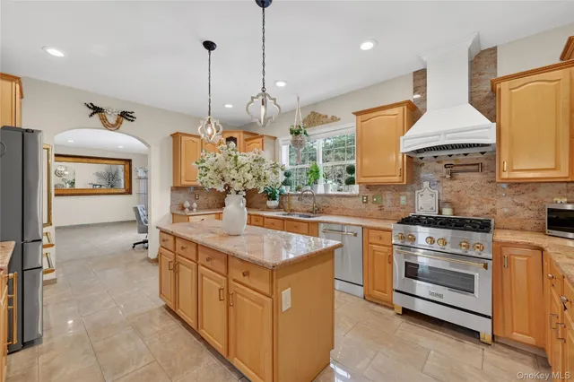 a kitchen with stainless steel appliances granite countertop a sink a stove and a wooden floor